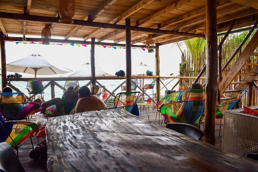A wooden deck with colorful chairs and umbrellas overlooking the sea. 3