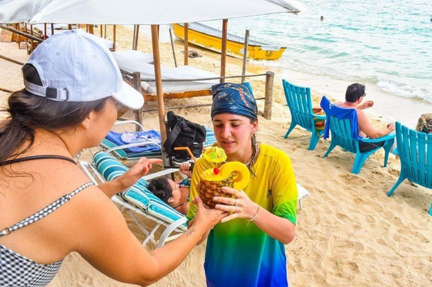 A beach scene with people relaxing on chairs, a woman handing a drink to a man, and a yellow boat in the background. 4