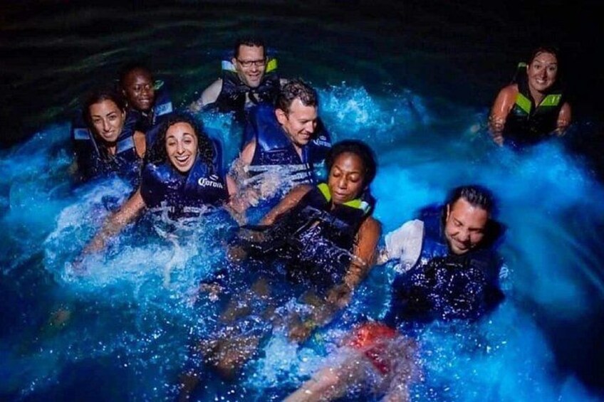 A group of people in water, wearing life jackets, with splashes around them. 2