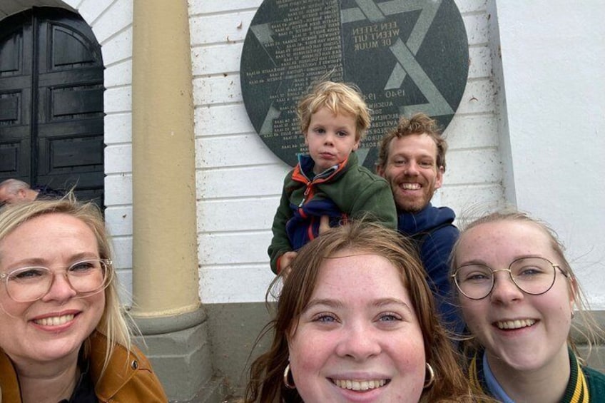 A family in front of a building with a plaque and a black door. 1