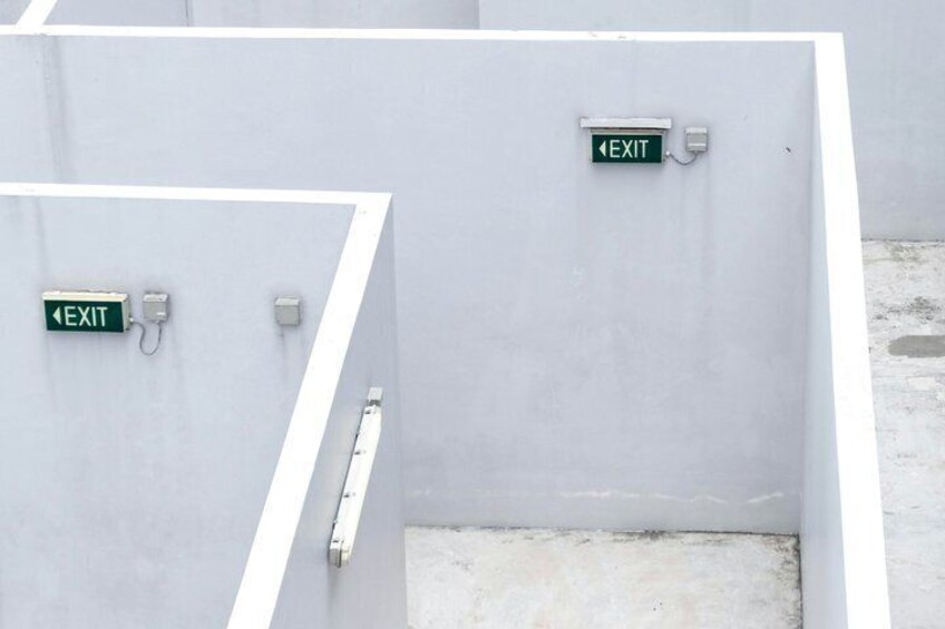 A building entrance with two EXIT signs, one above the other, and a metal handle on the door. 3