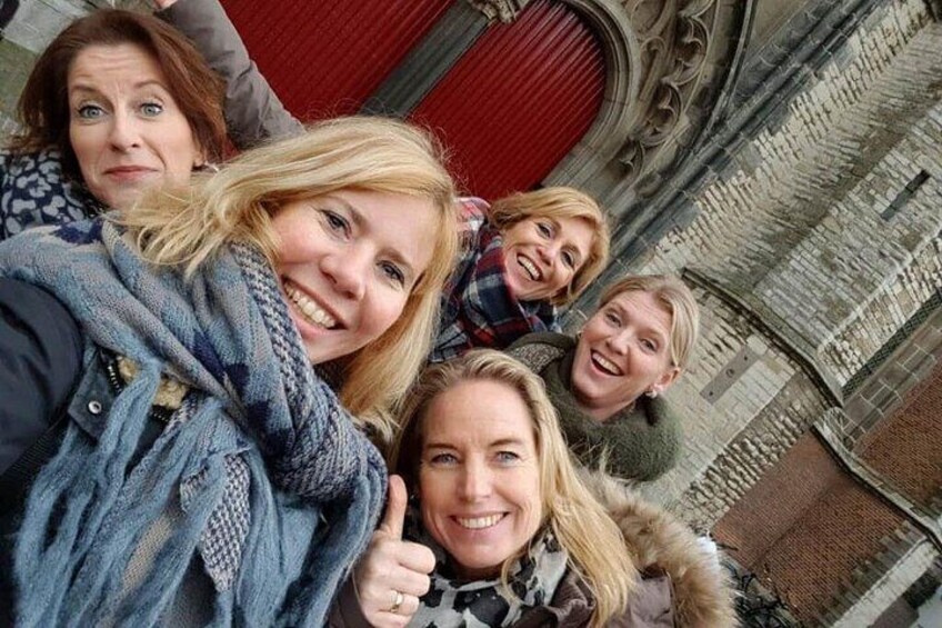 A group of people in front of a building with ornate stonework and a red door. 5