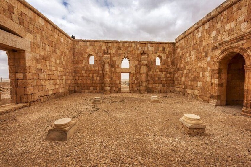 An ancient stone courtyard with arches and a central doorway. 4
