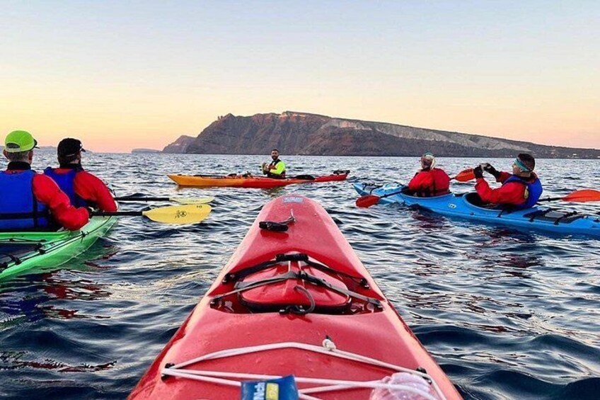 Un groupe de personnes pratiquant le kayak, naviguant sur des kayaks de différentes couleurs, sur une étendue d'eau calme, avec un paysage montagneux en arrière-plan. 4