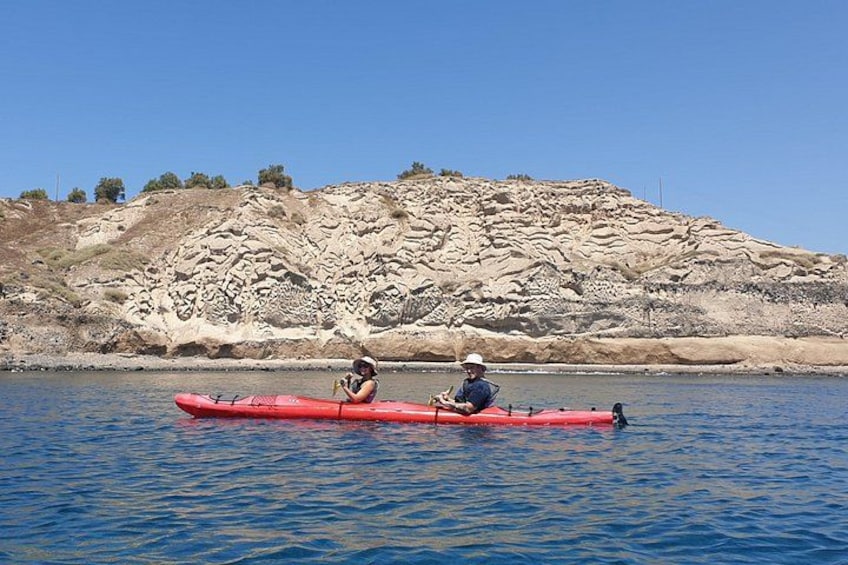 Deux personnes pratiquent le kayak sur une étendue d’eau calme, avec une colline rocheuse en arrière-plan. 5