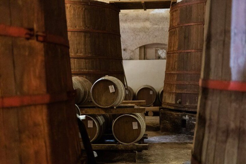 Wooden barrels stacked in a dimly lit storage area. 2