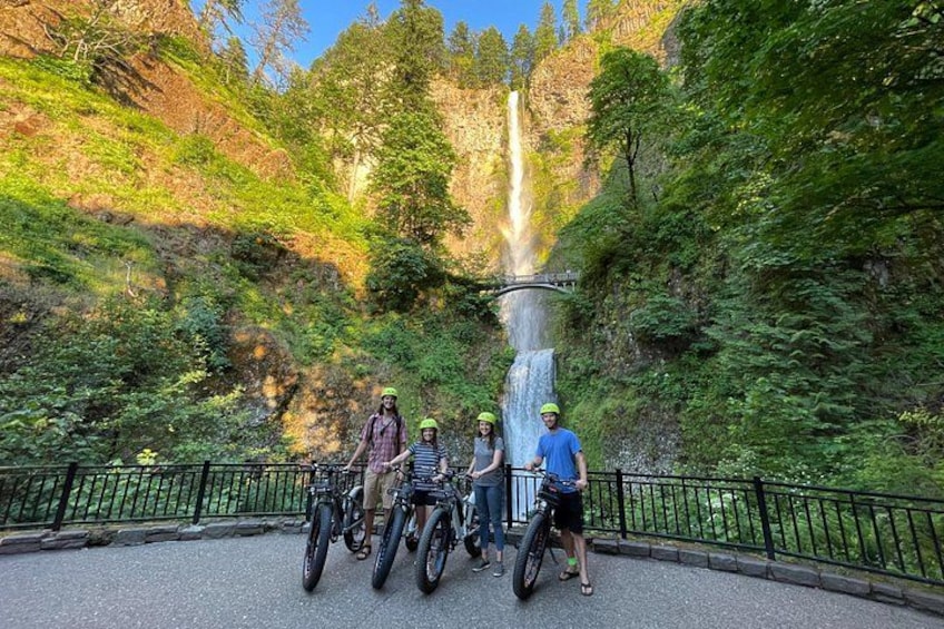 A group of people on bicycles near a waterfall in a forested area. 4
