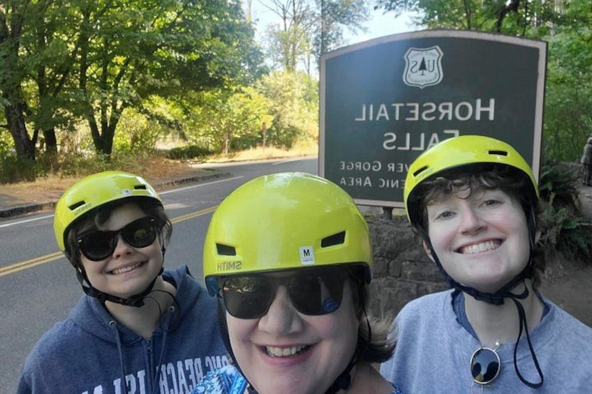 Three people wearing helmets, a road, and a sign that reads 'HOSPITAL'. 3