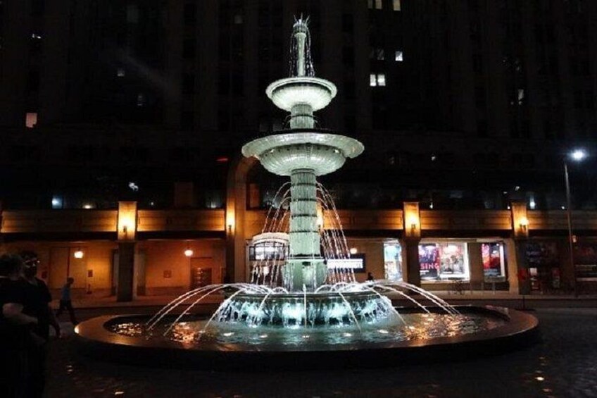 A multi-tiered fountain with water jets in a plaza at night. 2