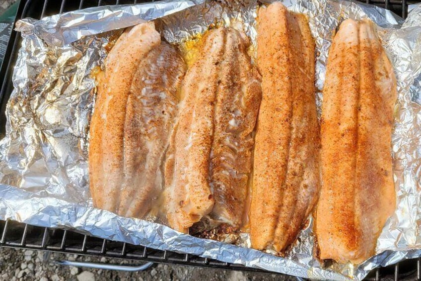 Three fish fillets on aluminum foil on a grill. 3