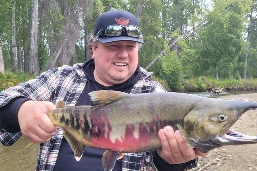 A person holding a large fish with a distinctive pinkish-red marking on its body. 2