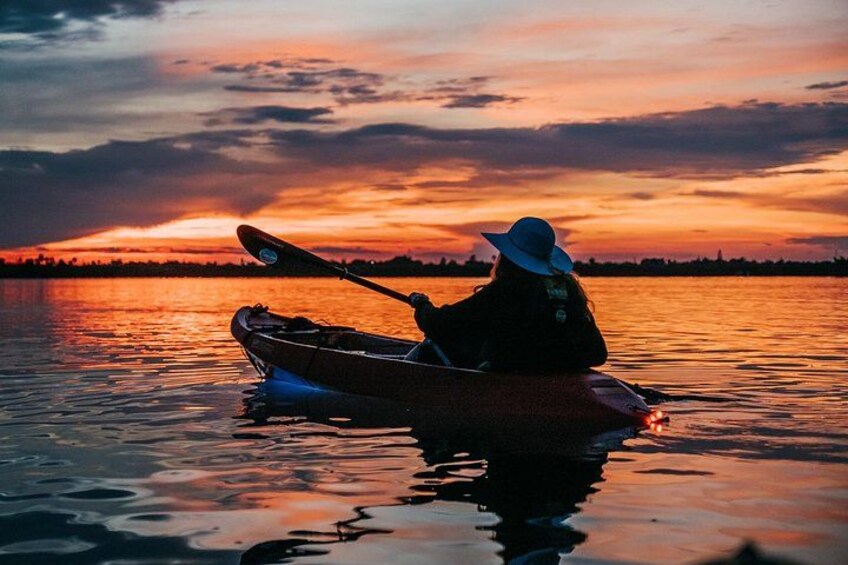 A person kayaking on a calm body of water during sunset. 4