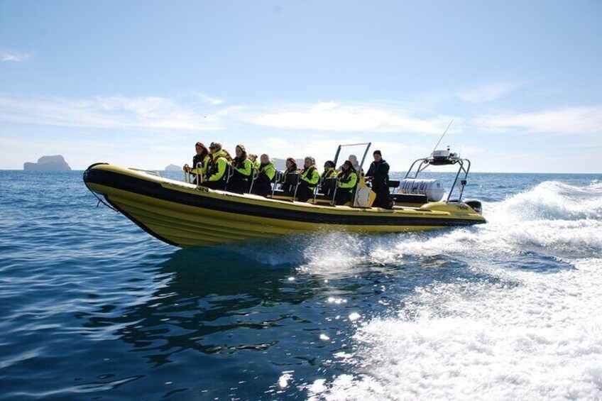 A yellow inflatable boat with people wearing life jackets on the water. 2