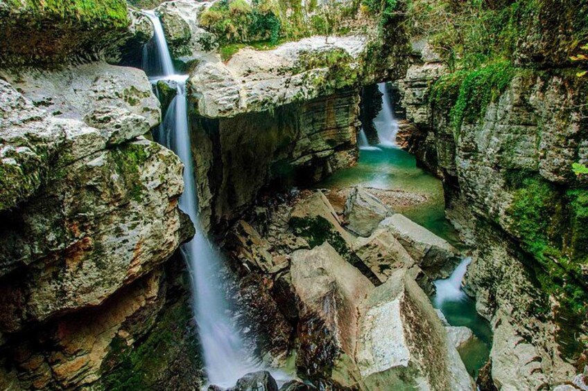 Ein Wasserfall stürzt über Felsen in bewaldeter Landschaft. 4