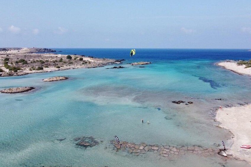 A coastal landscape with clear turquoise waters, rocky outcrops, and a sandy beach. 1