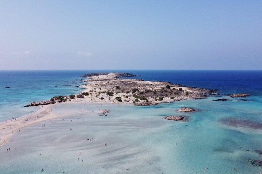 A coastal landscape with a sandy beach, clear turquoise waters, and rocky outcrops. 4