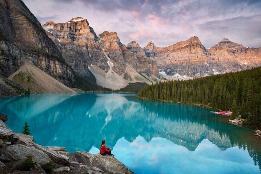 Une personne assise sur un rocher, au bord d’un lac turquoise, entourée de montagnes. 1