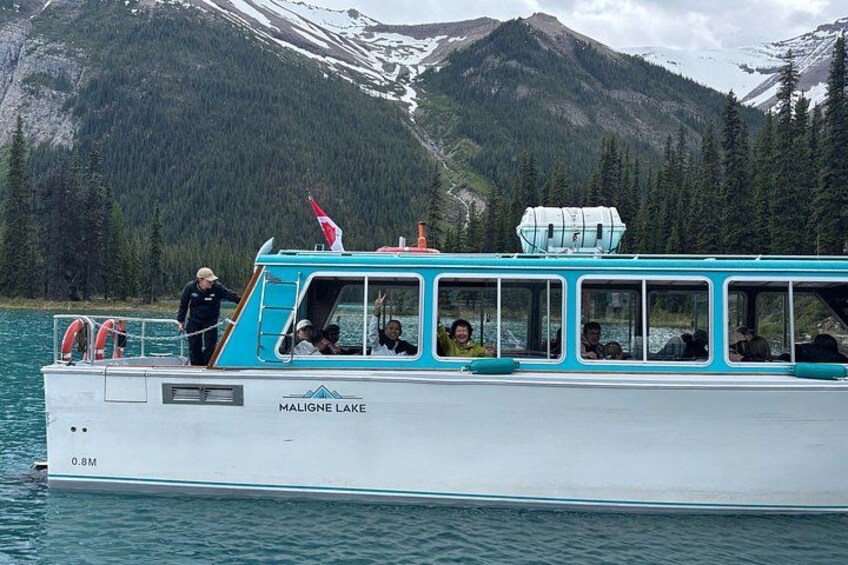 Un bateau nommé MALIGNE LAKE, transportant des passagers, est entouré de montagnes et d’arbres. 5
