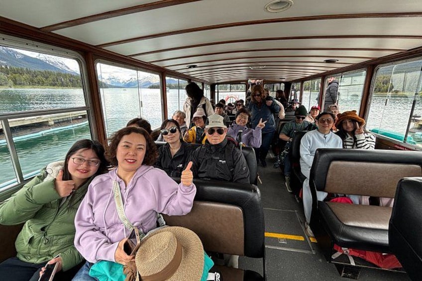 Un groupe de personnes se trouve sur un bateau, avec un lac et des montagnes en arrière-plan. 4
