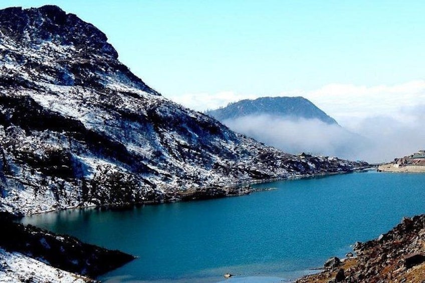 A snow-covered mountain, a calm lake, and a misty peak in the distance. 1