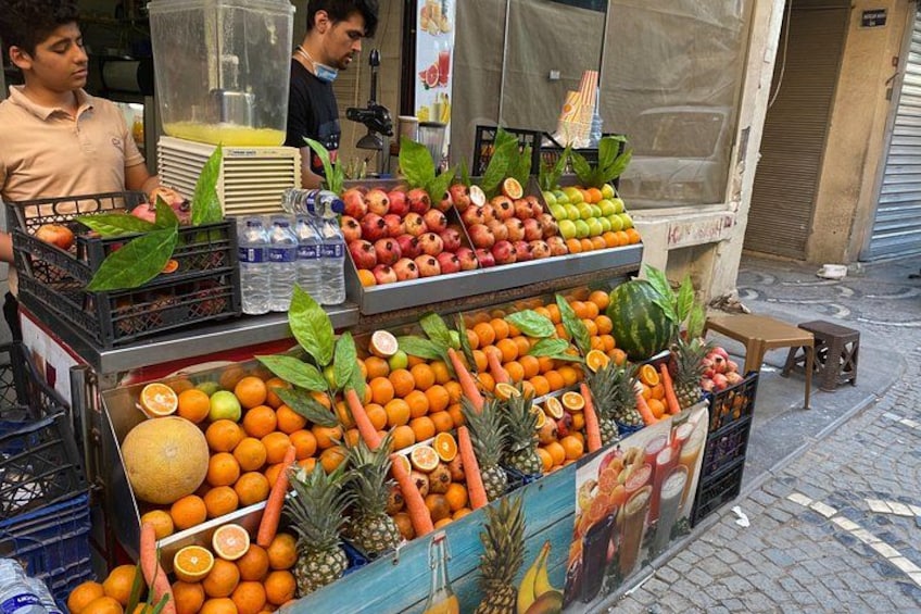 A fruit stand with various fruits and vegetables, including oranges, apples, and carrots. 1