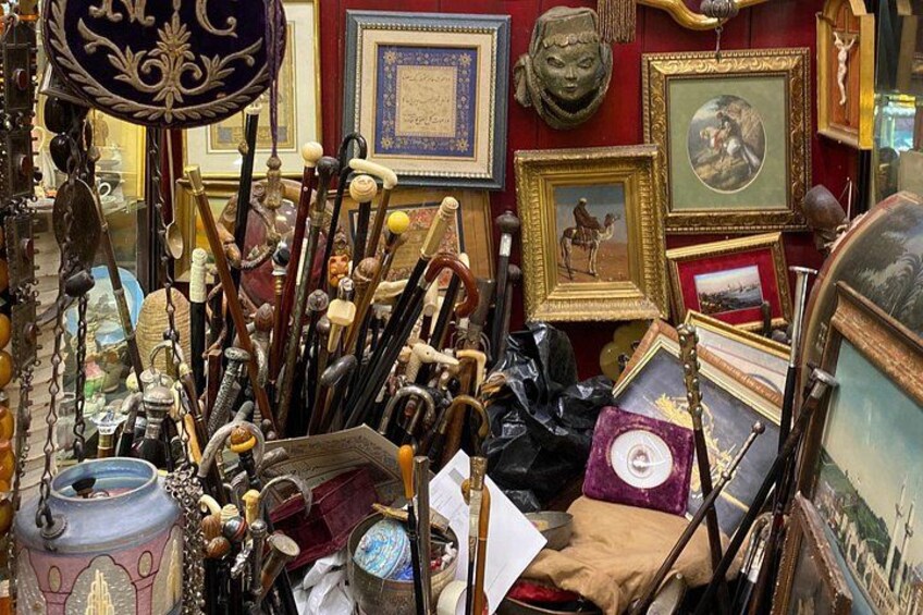 Een rommelige antiquariaat met diverse items, zoals ingelijste foto’s, vazen en decoratieve objecten. 1