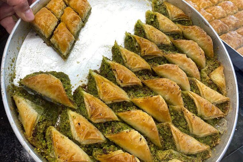Een schaal baklava met goudbruine filodeeg en een groene pistache vulling. 2