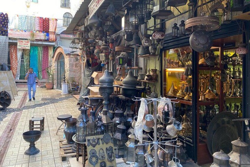 A market with various metal items and pottery displayed outside a shop. 5