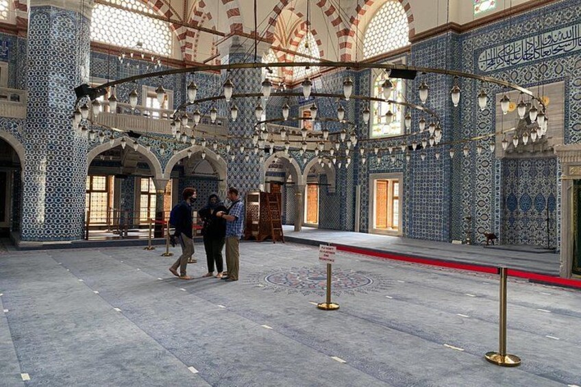 A large hall with intricate blue and white tile patterns, arched doorways, and hanging light fixtures. 2