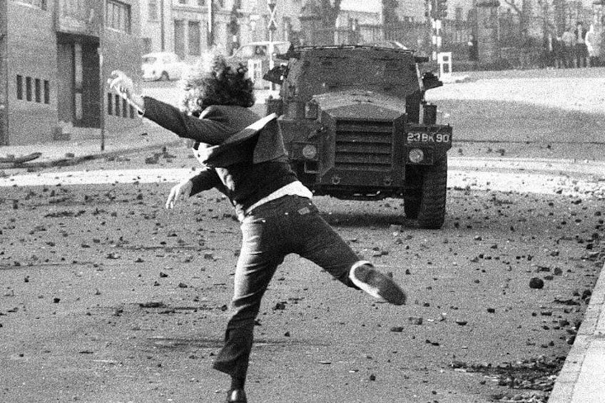 A person throwing a shoe at a military vehicle. 2