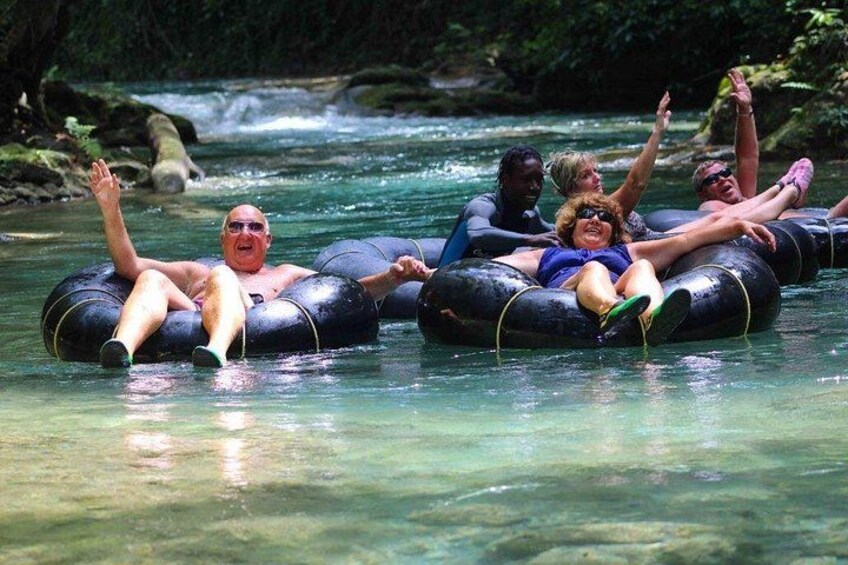People floating on intertubes in a river surrounded by greenery. 5