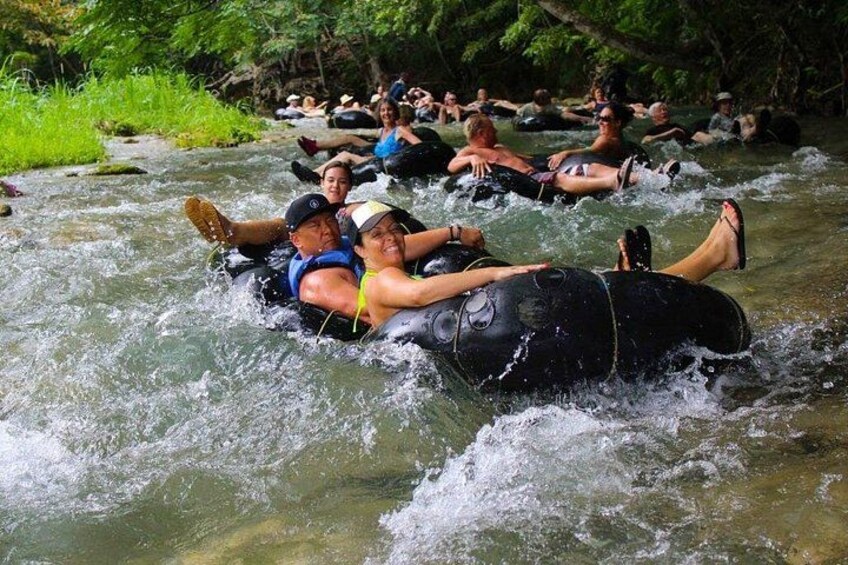 People floating on intertubes in a river surrounded by greenery. 4