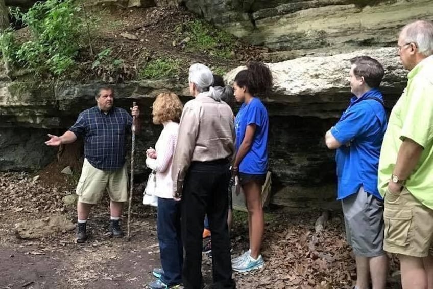 A group of people standing outdoors near a rocky cliff. 1