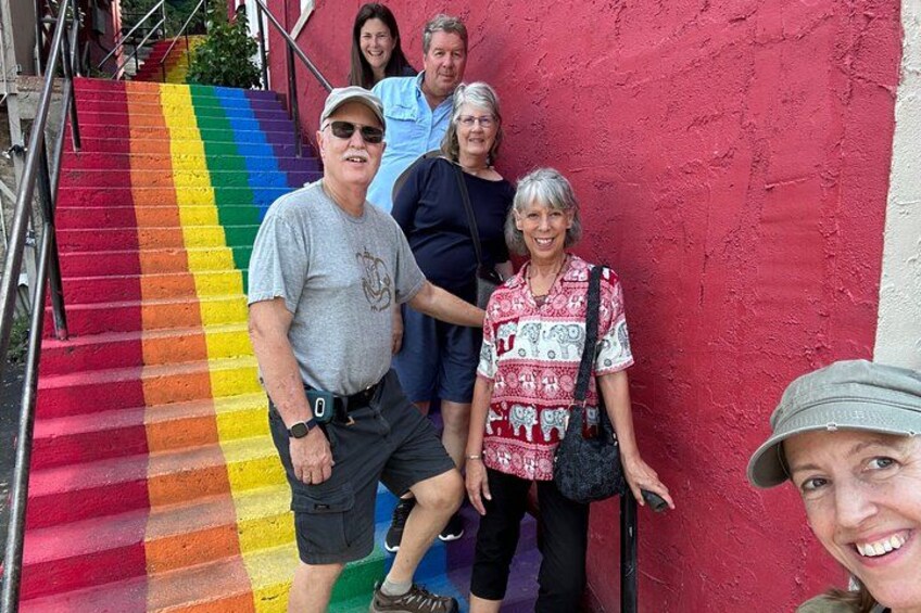 Un grupo de personas frente a una pared roja con una escalera de colores del arcoíris. 4