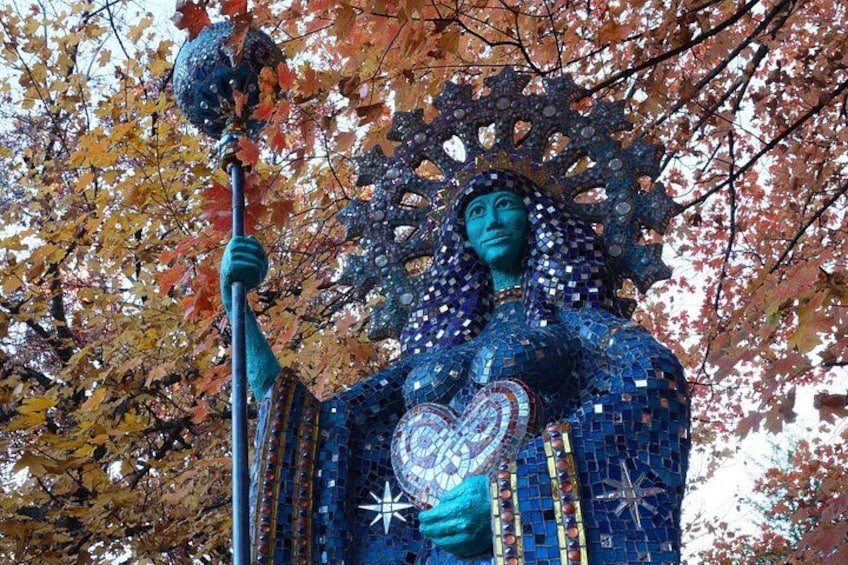 A mosaic statue of a figure holding a staff and a heart. 4