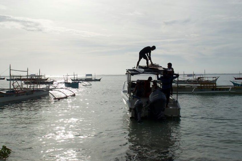 A boat with people on it, surrounded by calm water and other boats in the distance. 5