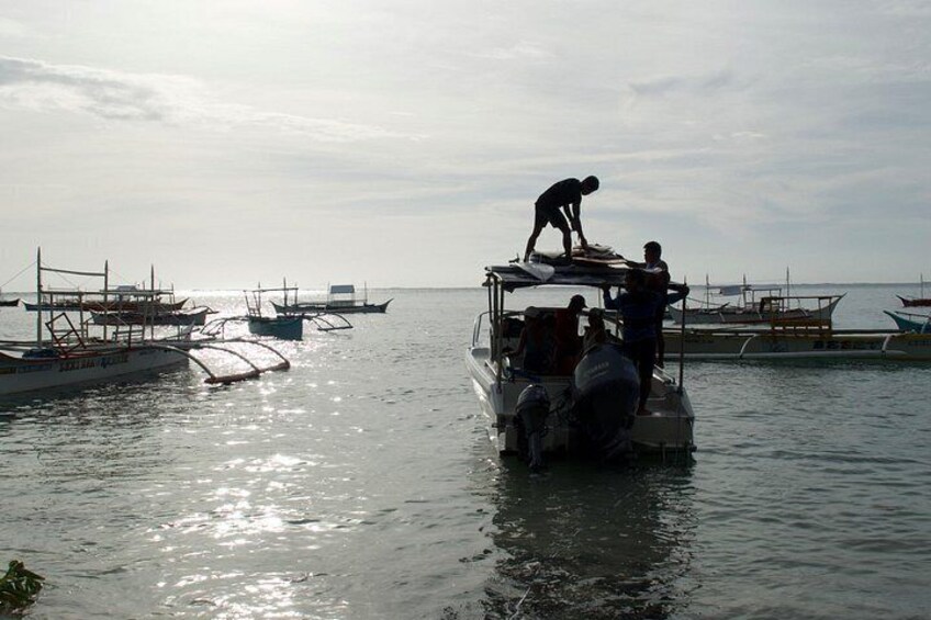 A boat with people on it, docked near other boats. 4
