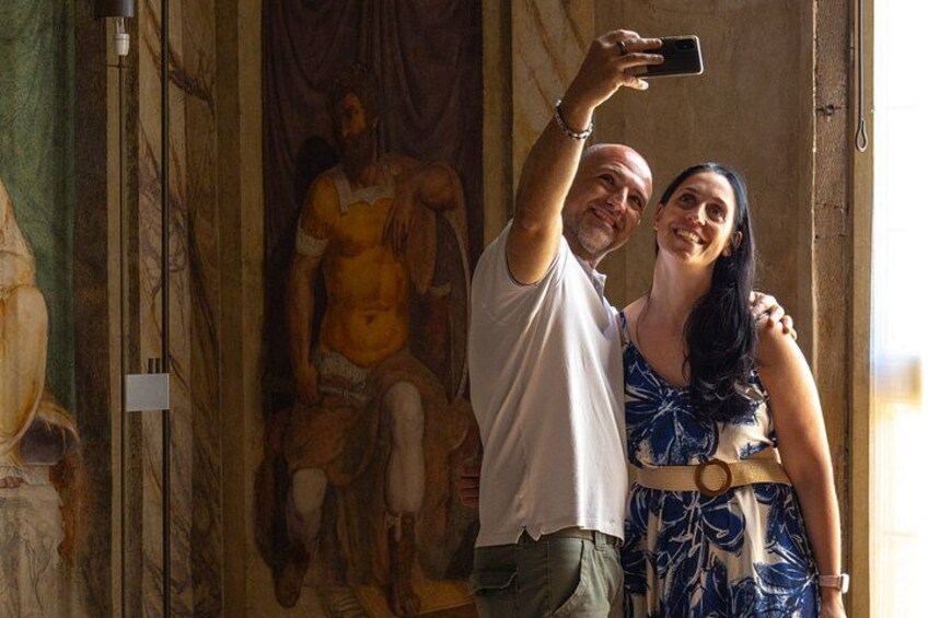 A person taking a selfie with a classical statue in the background. 3