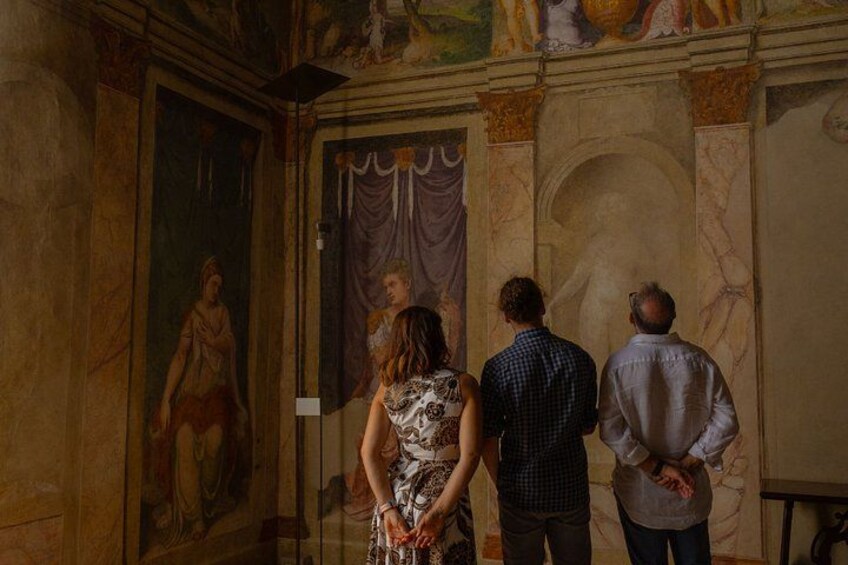 A group of people in a museum corridor with classical paintings and marble walls. 2