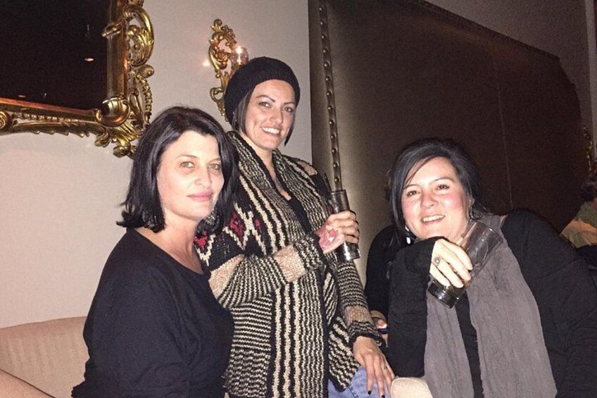 Three people standing indoors, one holding a drink. 5