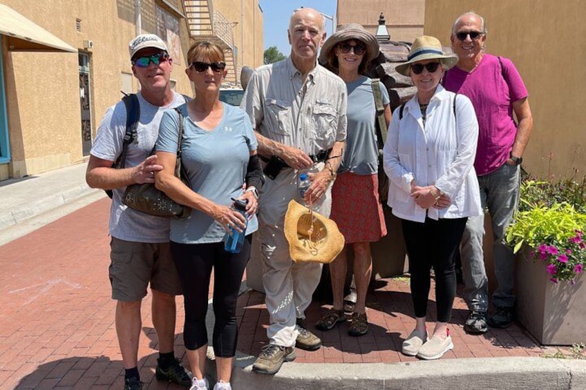 Un groupe de personnes se tient sur un chemin pavé de briques, avec des bâtiments en arrière-plan. 1