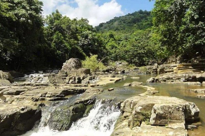 A waterfall cascading over rocks in a forested area. 2