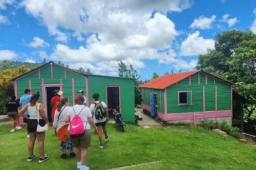 A group of people walking towards two small green buildings with red roofs. 3