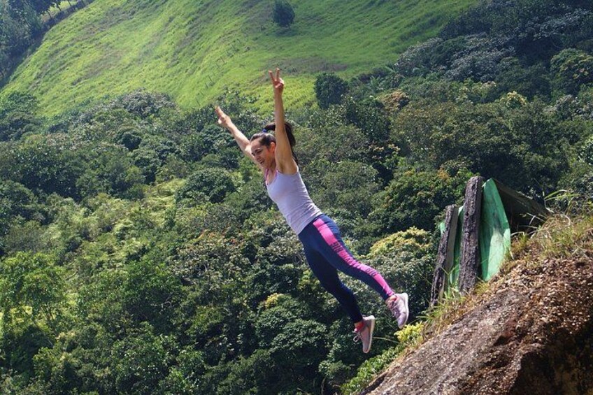 A person jumping off a cliff with a lush green valley in the background. 3