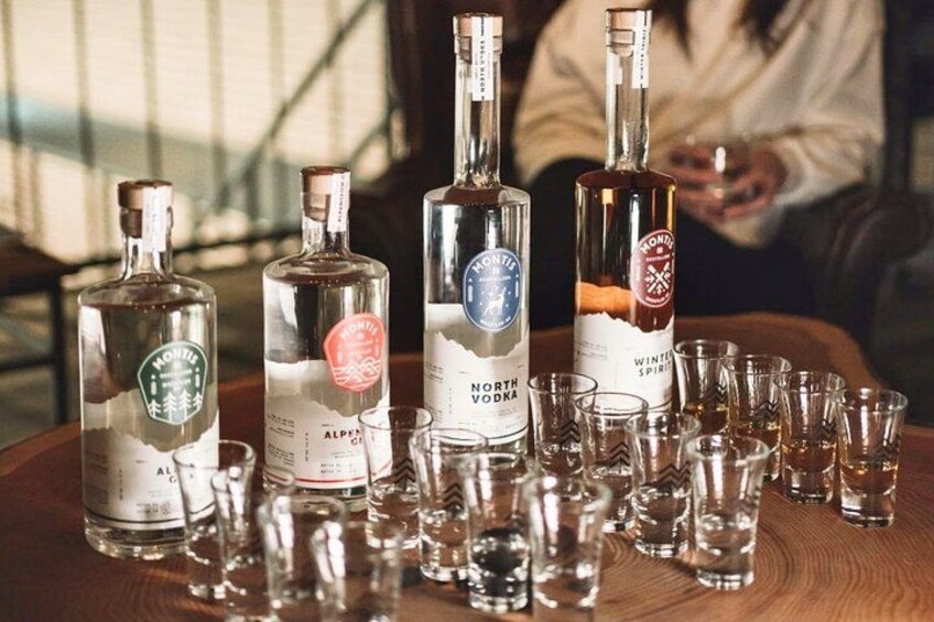 Three bottles of North Vodka on a wooden table with shot glasses. 2