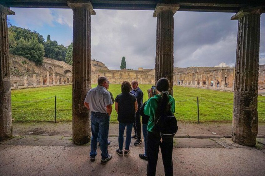 Tourists observing ancient ruins under a covered walkway. 4