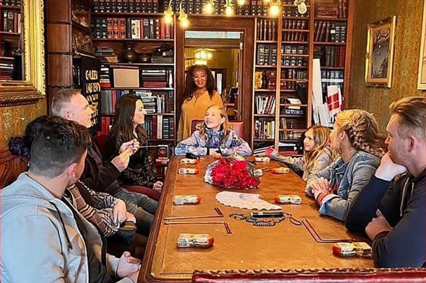 Un grupo de personas sentadas alrededor de una mesa de madera en una habitación con estanterías. 1