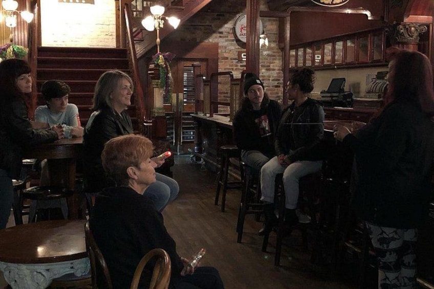 A group of people sitting at a bar in a rustic interior with wooden beams and a brick wall. 4