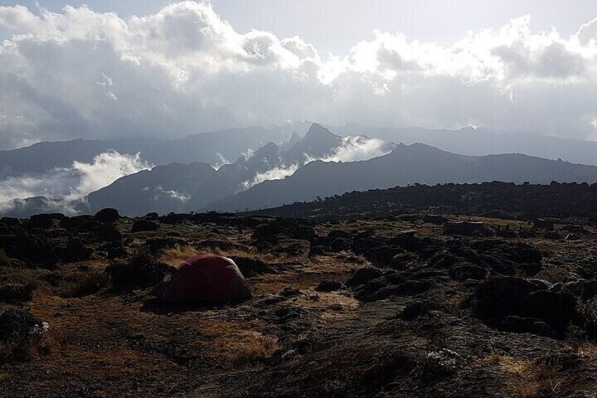 A rocky landscape with a red tent and distant mountains. 3