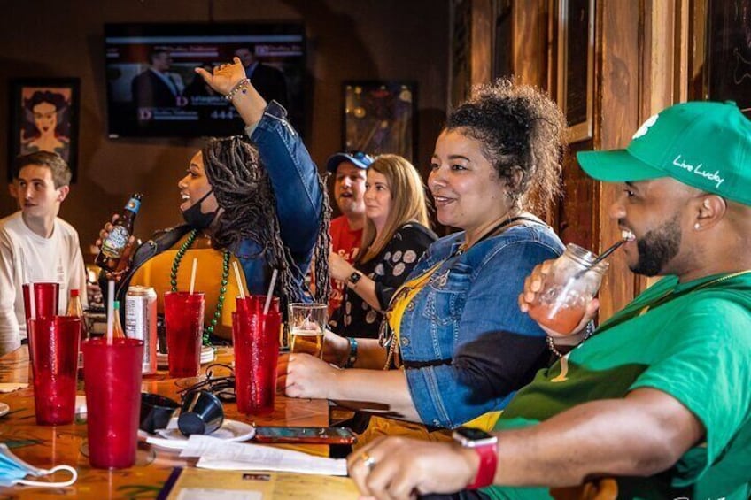 Un groupe de personnes est assis au bar, devant des gobelets et des bouteilles en plastique rouge. 1